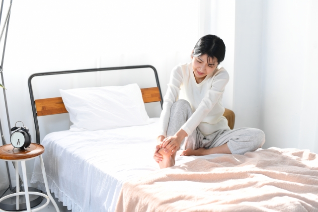 起床して早々外反母趾の痛みが辛い女性のイメージ画像