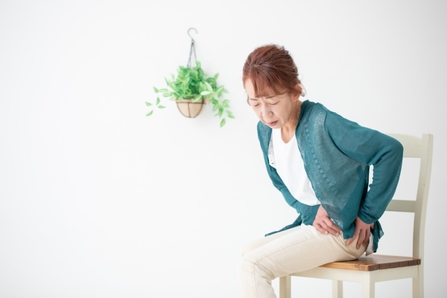 しばらく座っていて立とうとすると股関節の痛みが出てしまう女性のイメージ画像
